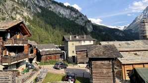 A mountain village with traditional wooden houses, a stone building, and a view of snow-capped mountains. - Swiss mountain chalet, wooden interior, cosy, with a beautiful view (Evolène)