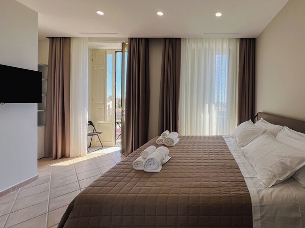 Deluxe driepersoonskamer, gedeeltelijk uitzicht op zee | Een kluis op de kamer, een bureau, verduisterende gordijnen, gratis wifi