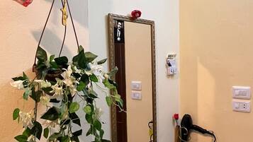 Un baño con espejo, lavamanos y una planta colgante.