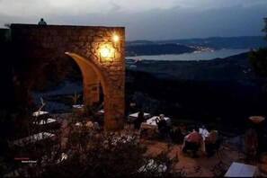 A stone archway with a light fixture, overlooking a scenic view of a lake and distant hills. - AL-Bustan House & Umm Qais  (Umm Qais)
