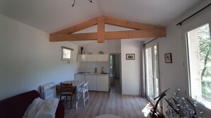 A spacious living area with a wooden ceiling, a dining table, and a kitchen in the background. - Country cottage, calm and relaxation in the sun. (Sainte-Croix-à-Lauze)
