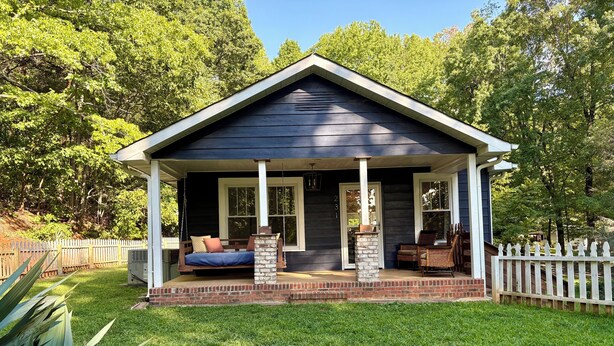 Ein Haus mit Veranda, Schaukel und Ziegelstütze.