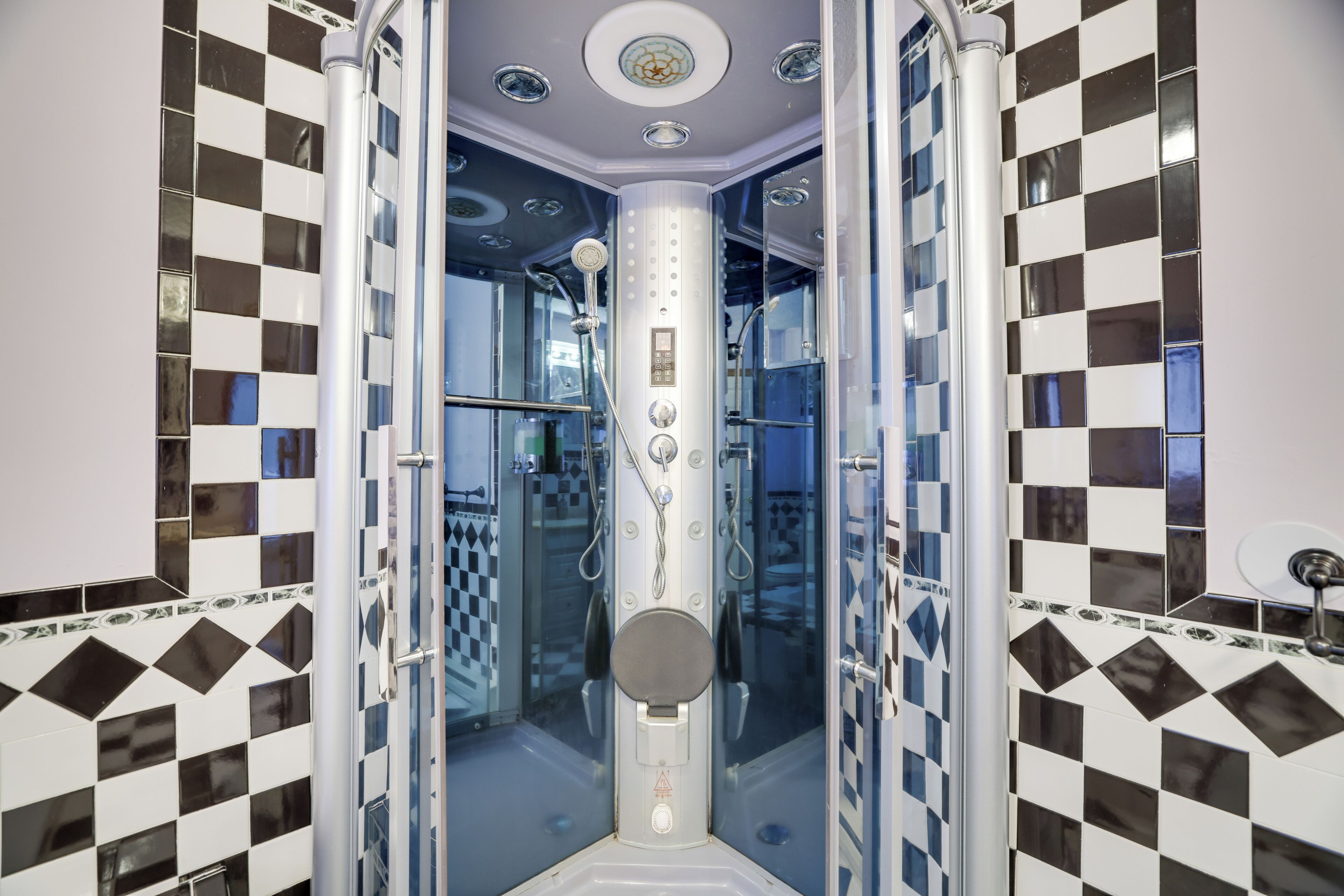 A modern bathroom with a checkered tile design, a glass-enclosed shower, and a control panel.