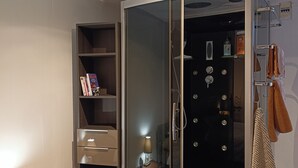 Habitación con puerta de vidrio corrediza, una mesita con lámpara y un cubo de basura.