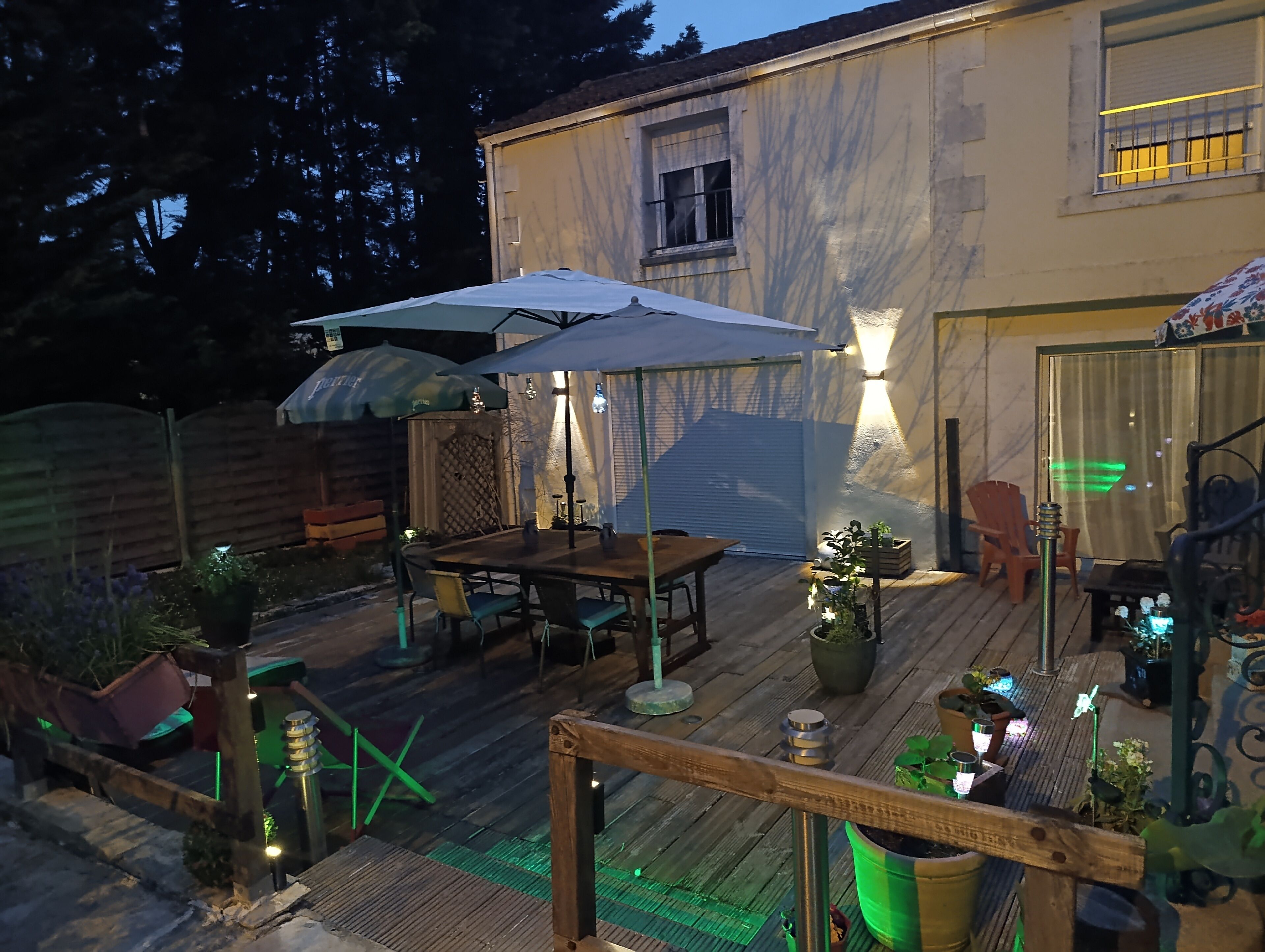Un patio con terraza de madera, mobiliario exterior y plantas en macetas.