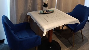 Una habitación con una mesa preparada para dos, dos sillas azules, una orquídea en maceta y una bandeja con objetos.