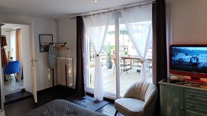 Una habitación de hotel con una cama, una silla, televisión y vistas al exterior.