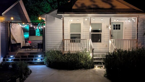 Una casa con porche, escalones y luces colgantes.
