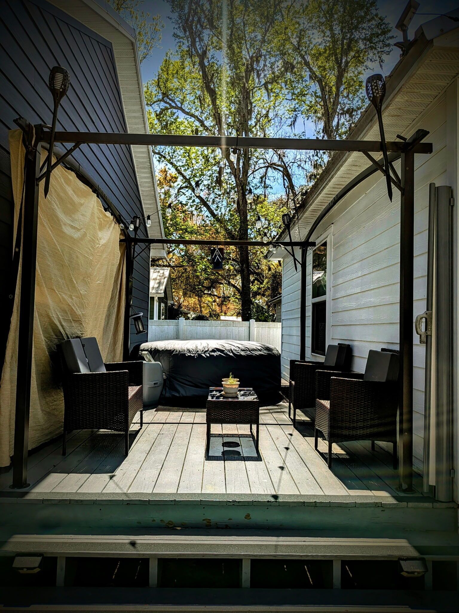 An outdoor patio with a covered seating area, a table, and chairs.