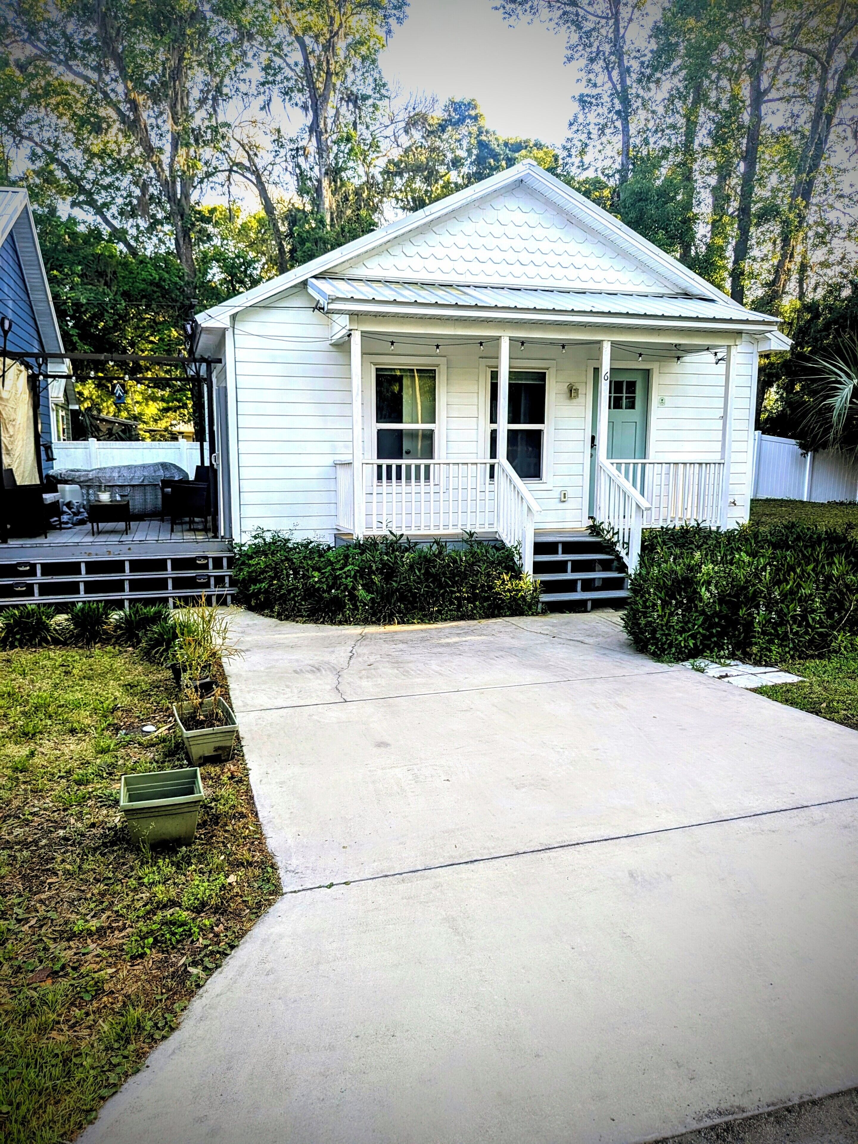 Uma casa térrea com varanda da frente, pequeno jardim frontal e entrada por meio de um acesso de veículos.