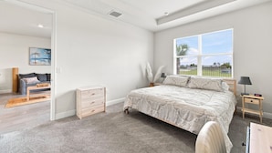 Een slaapkamer met een groot bed, een raam met uitzicht, een nachtkastje en een stoel.