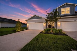 A residential house with a garage, a well-maintained lawn, and a clear sky.