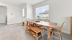 A dining area with a wooden table and chairs, a bench, and a window with blinds.