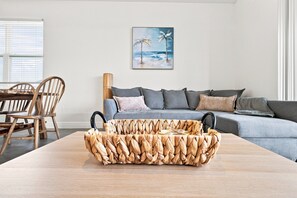 A living room with a sofa, a coffee table, and a painting of a beach scene.