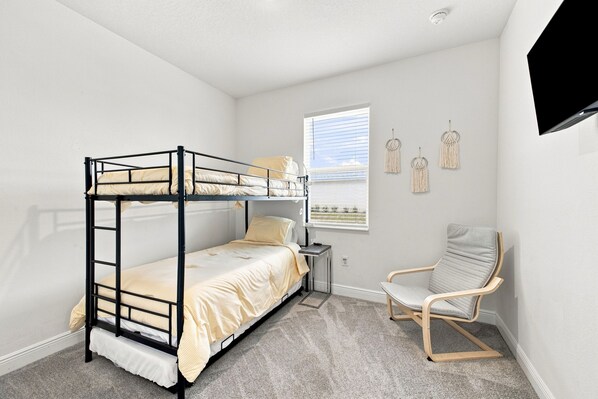 A bunk bed room with a desk, chair, and wall decorations.