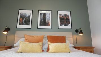 Un lit bien fait, avec deux oreillers, une tête de lit et trois tableaux encadrés accrochés au mur.