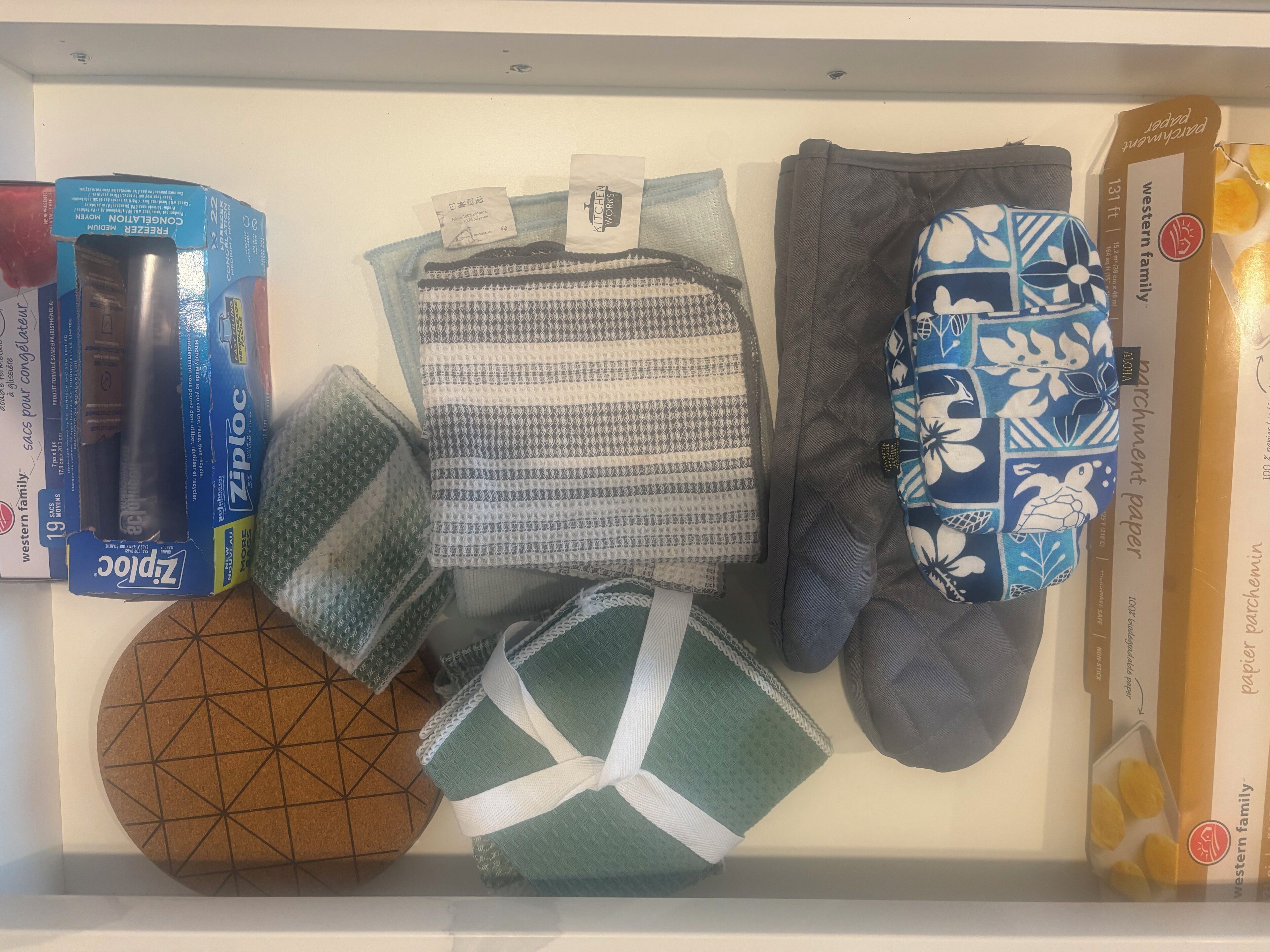 A drawer containing various items including a box of Ziploc bags, a patterned fabric, a pair of socks, and a decorative bowl.