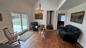 A spacious living room with a fireplace, a chandelier, and a dog. - Large 3-bedroom house in a quiet neighborhood in the village of Canton, NY (Canton)