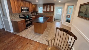 A spacious kitchen with wooden cabinets, a large island, and a dining area with a wooden chair. - Large 3-bedroom house in a quiet neighborhood in the village of Canton, NY (Canton)