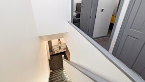 A staircase leading to a bedroom with a bed and a nightstand. - Spacious and Comfortable Modern Rooms (Clayton)