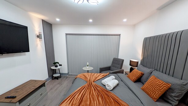 A modern hotel room with a large bed, a flat-screen TV, a small table, and a chair. - Spacious and Comfortable Modern Rooms (Clayton)