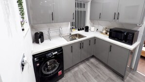 A modern kitchen with grey cabinets, a built-in dishwasher, a microwave, and a sink. - Spacious and Comfortable Modern Rooms (Clayton)