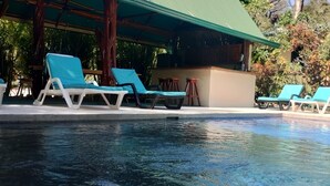 Ein Poolbereich mit Liegestühlen und einer Bar.