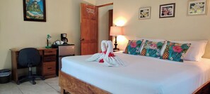 A hotel room with a bed, a desk with a chair, a coffee maker, and a door. - Casa 'Ohana- Charming 3-bedroom house w/ WiFi, AC, pool, in lovely Playa Guiones (Guanacaste Province)