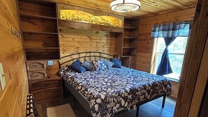 Een houten slaapkamer met een bed, nachtkastjes en een raam met gordijnen.