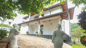 A white building with a stone-paved entrance and two statues. - Villa Victoria Edge  (Digana)