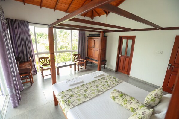 A bedroom with a bed, wooden furniture, and a view of greenery outside. - Villa Victoria Edge (Digana)