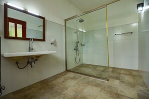 Une salle de bain avec une douche à parois de verre, un lavabo avec un miroir et un revêtement de sol carrelé.
