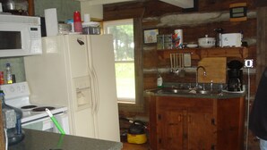 Cocina compacta con refrigerador, estufa, microondas y gabinetes de madera.