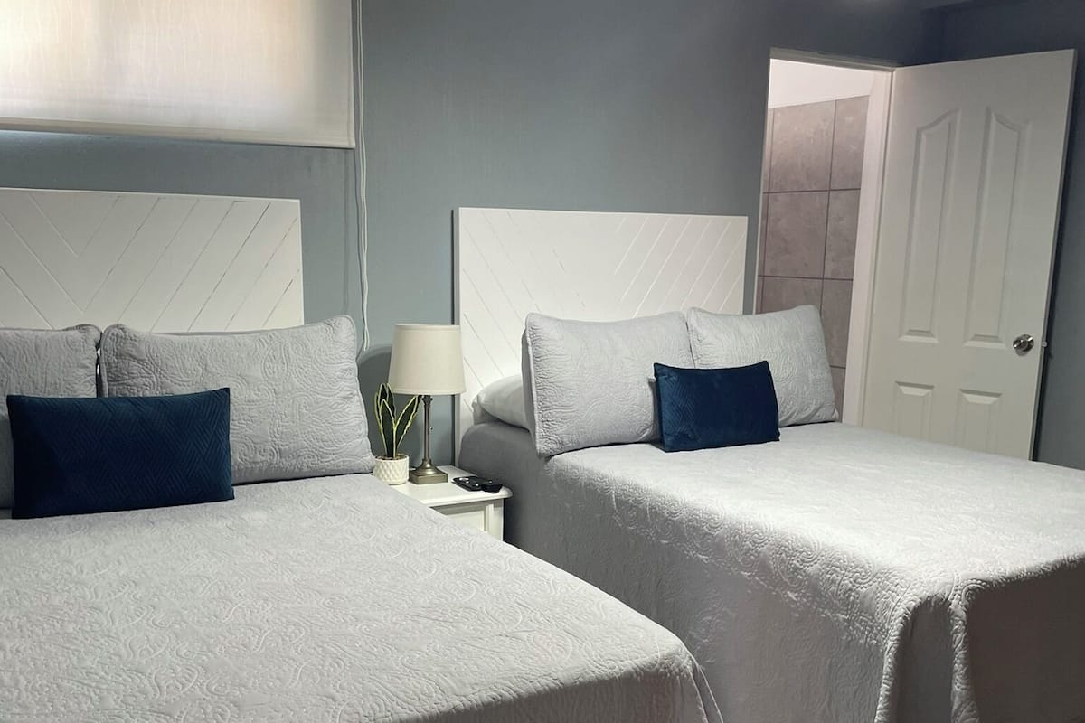 Une chambre d’hôtel avec deux lits, une table de chevet, une lampe et une porte.