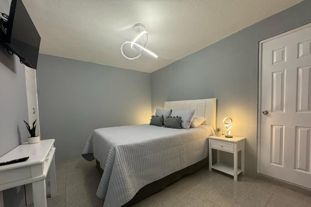 Une chambre à coucher avec un lit, une table de chevet et un bureau avec une chaise.