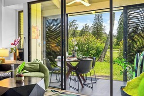 A modern interior with a dining area, a sofa, and a view of the outdoors.
