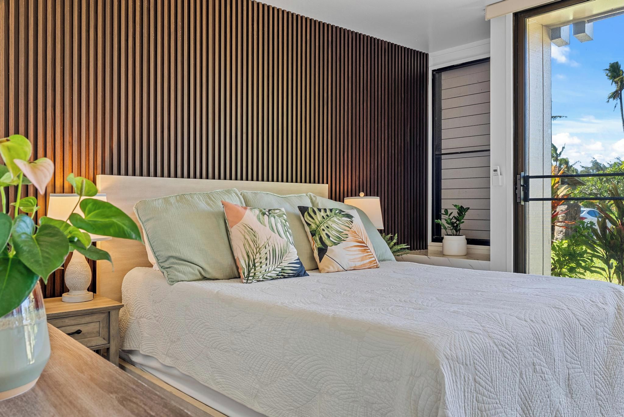 Quarto com cama, mesas de cabeceira e vista para o exterior.