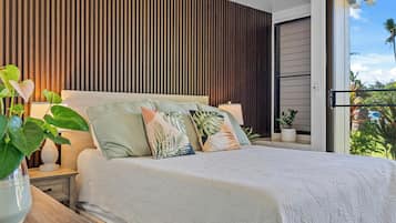 A bedroom with a bed, bedside tables, and a view of the outdoors.