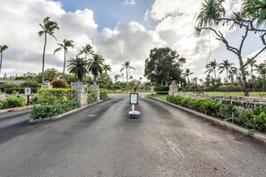 A road leading to a gated entrance with a sign indicating a 10-minute drive to the airport.