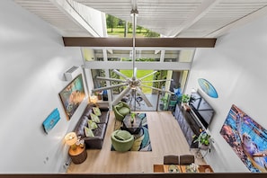 A modern interior with a central ceiling fan, a dining area with a table and chairs, and a seating area with sofas and a coffee table.