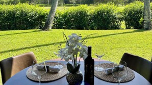 Mesa de comedor al aire libre con vista a un jardín cuidado y árboles.