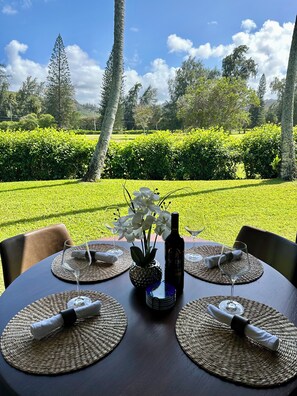 A dining table set outdoors with a view of a manicured garden and trees.