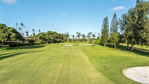 A golf course with a clear sky, well-maintained grass, and sand bunkers.