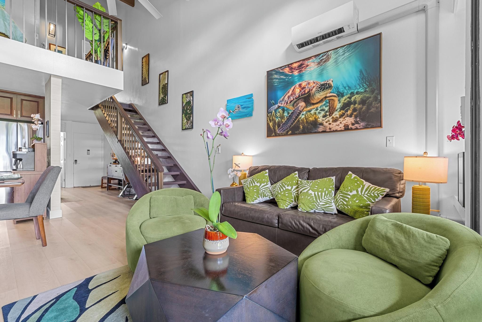 A modern living room with a staircase, a dining area, and a kitchen.