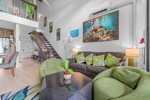 A modern living room with a staircase, a dining area, and a kitchen.