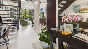 Un interior moderno con una escalera, un comedor y un espacio de sala de estar con vistas.