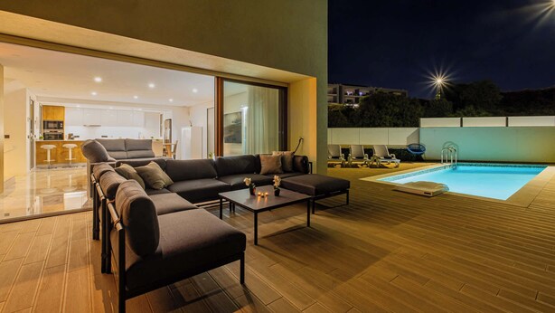 Un espacio exterior con piscina, sofá y zona de comedor.