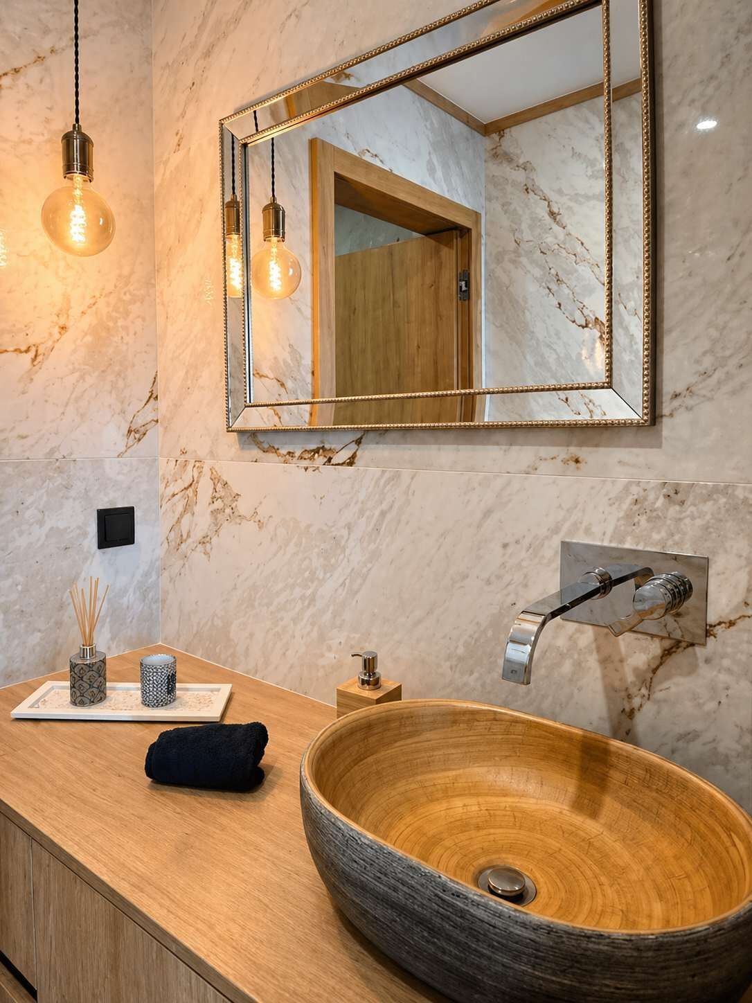 Een badkamer met een houten wastafelmeubel, een marmeren spatwand, een grote spiegel en een waskom.