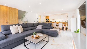Una sala de estar moderna con un sofá seccional, una mesa de centro y una cocina al fondo.