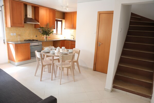 A modern kitchen with wooden cabinets, a gas stove, and a dining area with a round table and chairs.